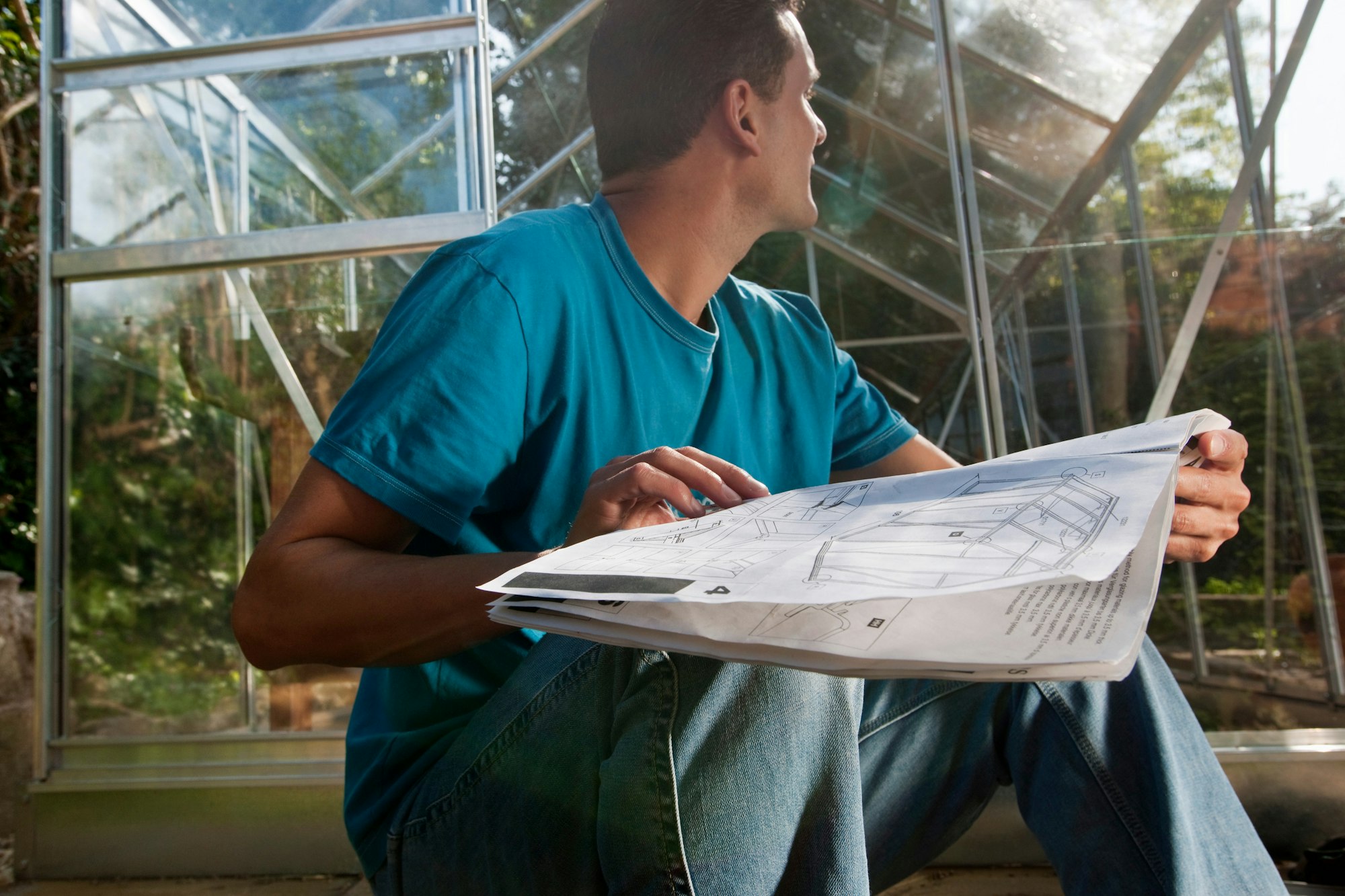 Man with greenhouse plans in garden